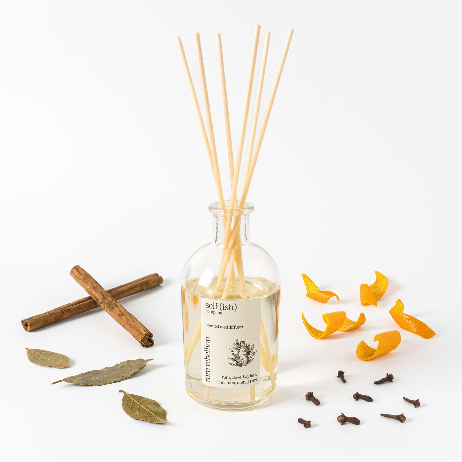 scented reed diffuser in clear glass bottle with cinnamon bay leaf clove and orange peel