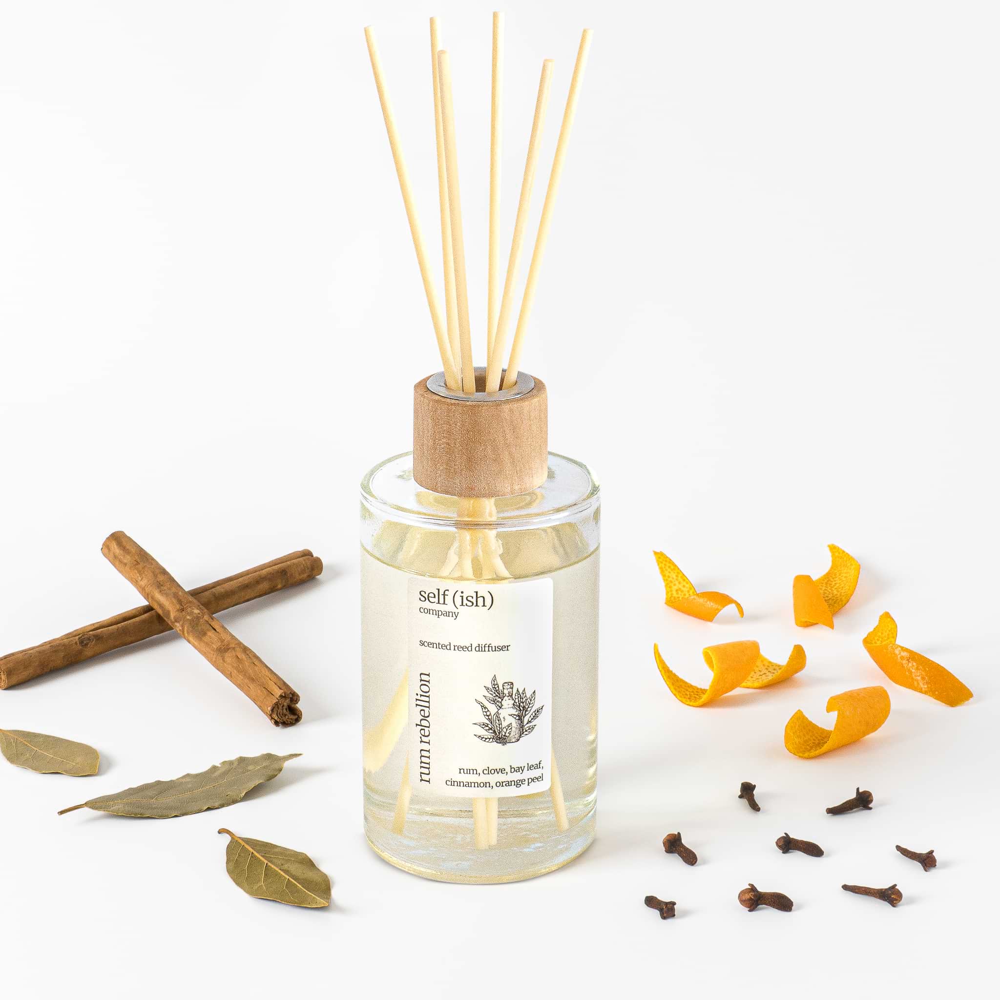 scented reed diffuser in clear glass bottle with cinnamon bay leaf clove and orange peel