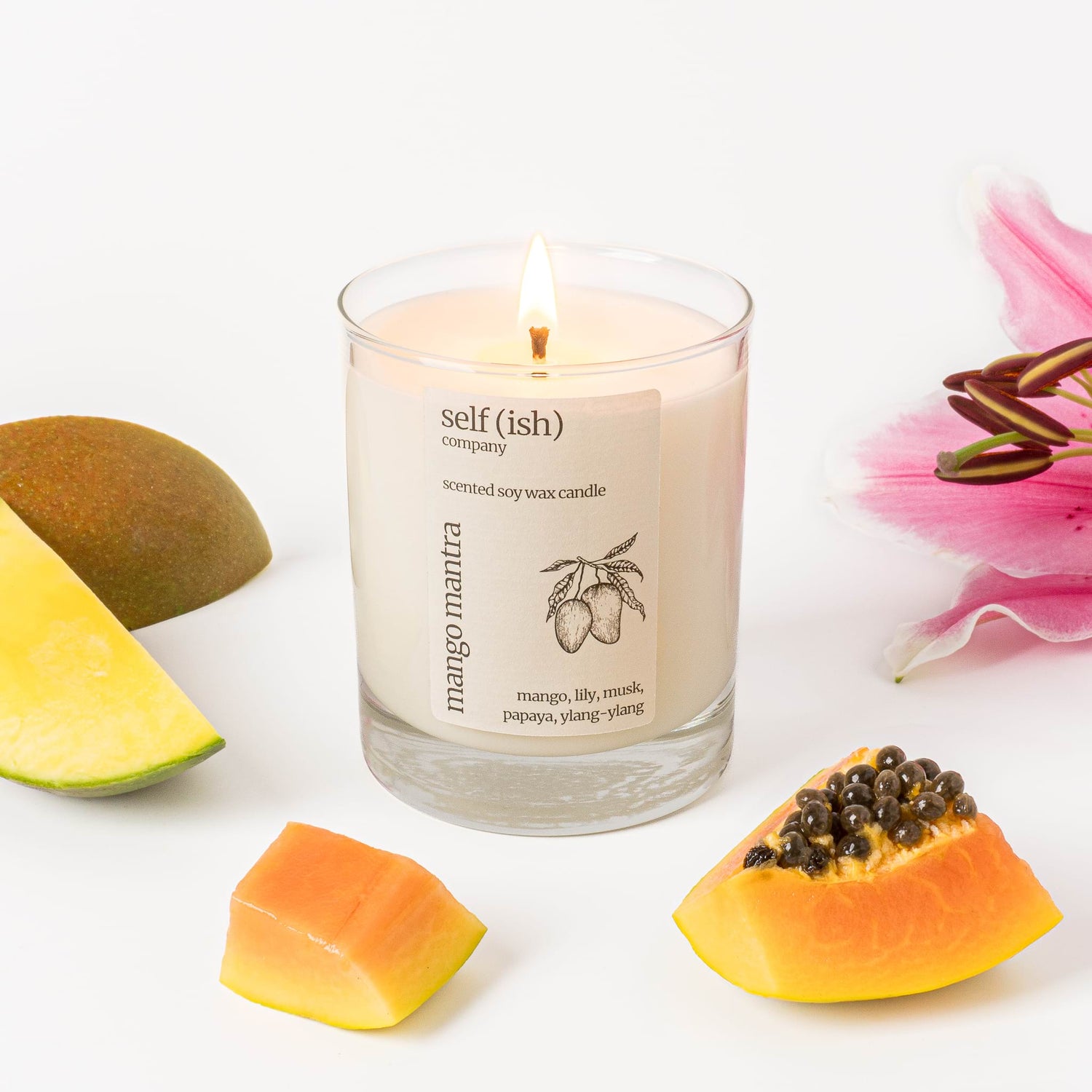 burning soy candle in clear glass container with mango papaya and lily