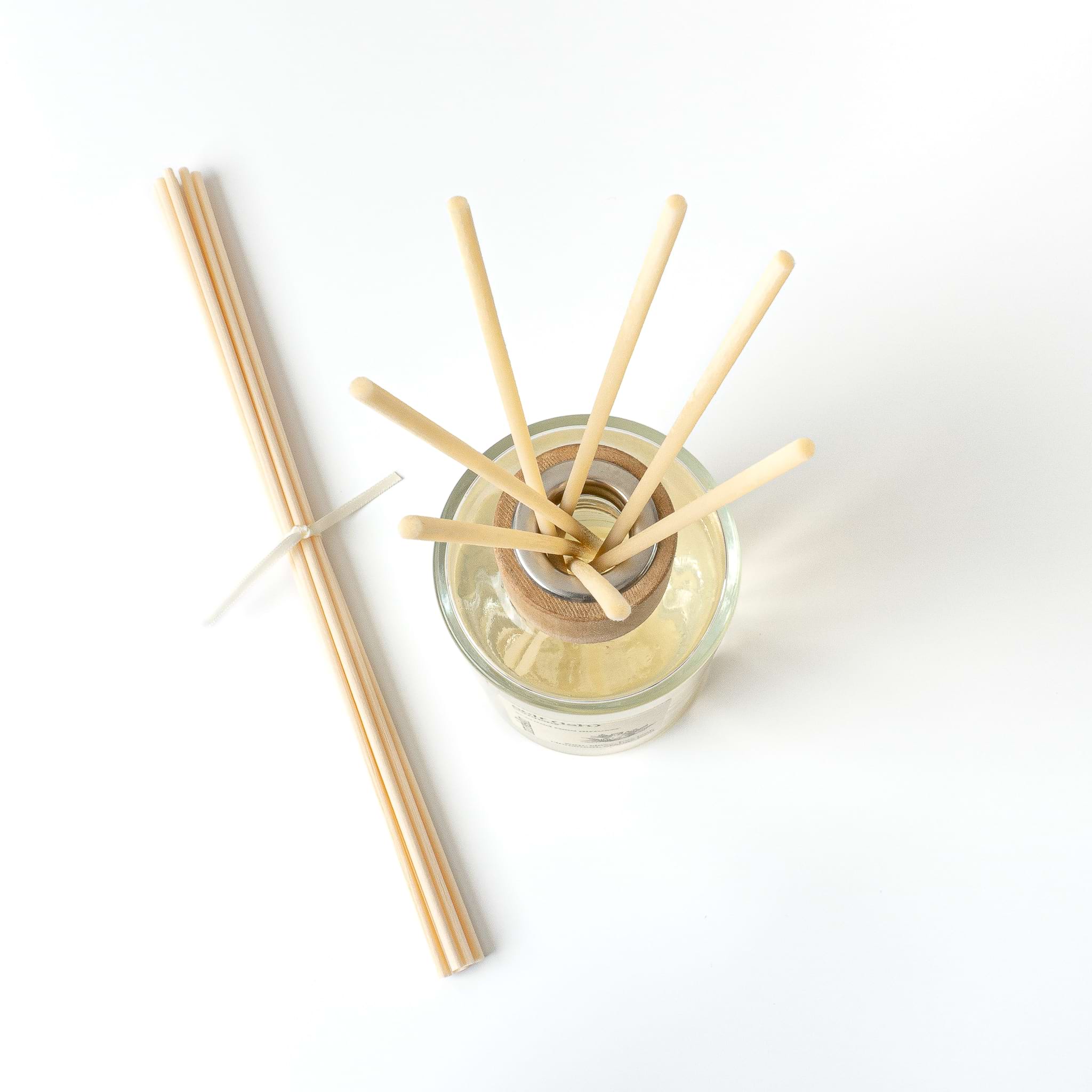 Luxury reed diffuser in glass bottle with wooden cap birdseye view from above with reeds and white background