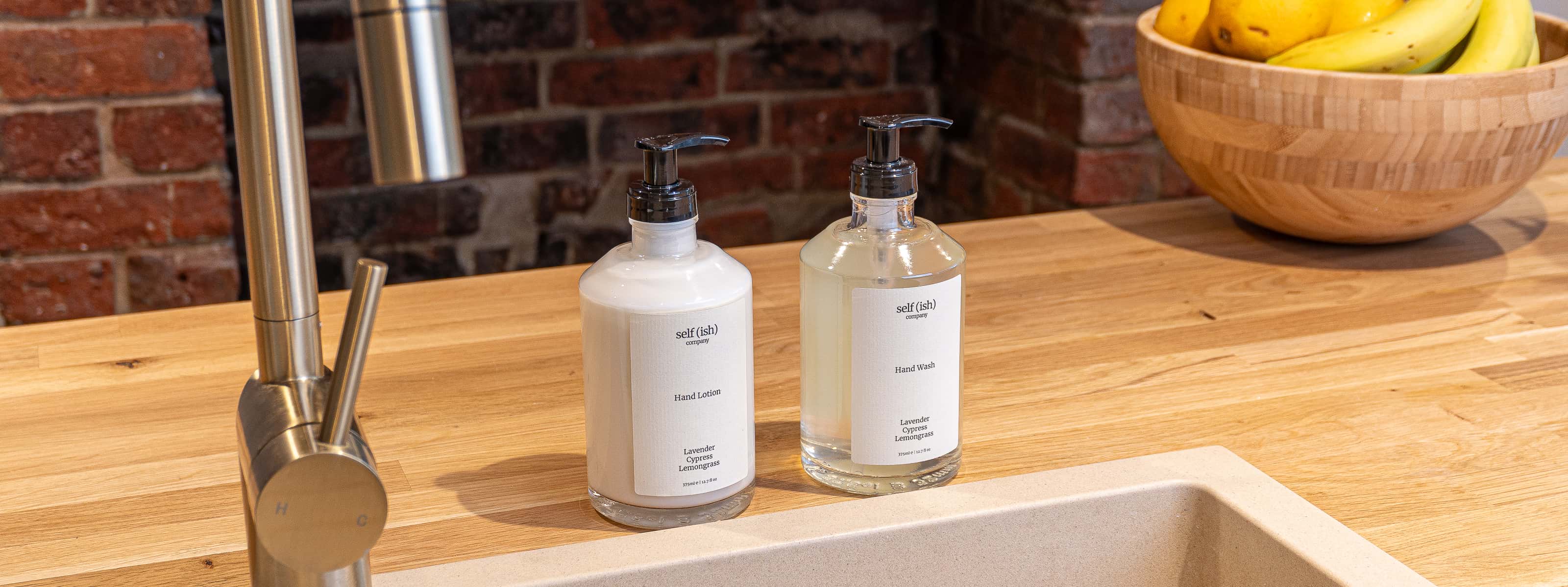 Bottles of hand wash and hand lotion on a wooden kitchen counter